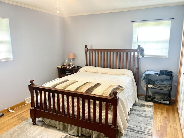 bedroom featuring wood finished floors, crown molding, and baseboards