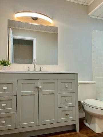 full bathroom featuring ornamental molding, wood finished floors, toilet, and vanity