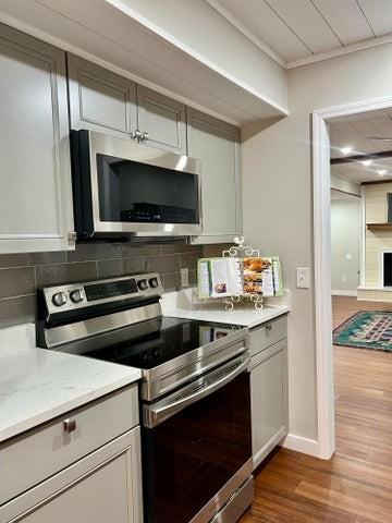 kitchen featuring appliances with stainless steel finishes, dark wood-type flooring, backsplash, baseboards, and crown molding