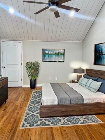 bedroom featuring lofted ceiling, wood finished floors, a ceiling fan, and wooden ceiling