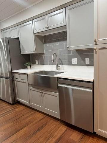 kitchen with stainless steel appliances, a sink, light countertops, backsplash, and ornamental molding