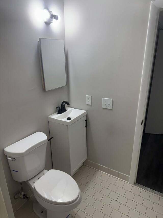 half bath featuring toilet, vanity, and tile patterned floors