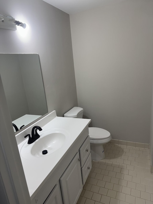 half bathroom featuring vanity, toilet, tile patterned flooring, and baseboards