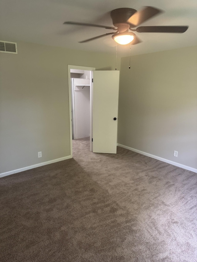 carpeted spare room featuring a ceiling fan and baseboards