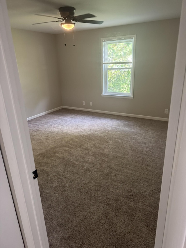 carpeted empty room featuring ceiling fan and baseboards
