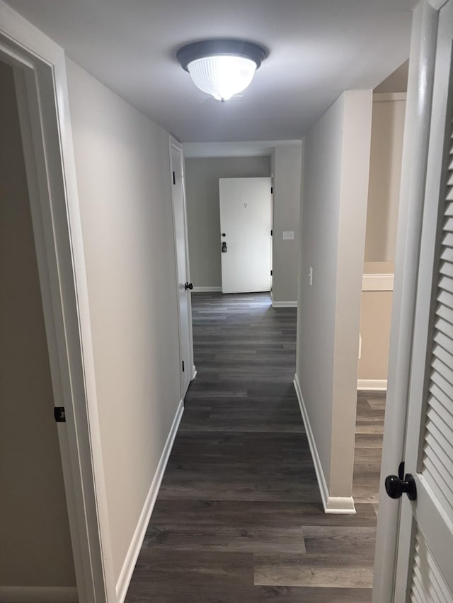 hallway with dark wood-style flooring and baseboards