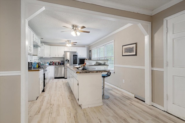 1505 Roane St, Covington, TN 38019 - kitchen featuring stainless steel appliances, ornamental molding, a ceiling fan, light wood finished floors, and a breakfast bar