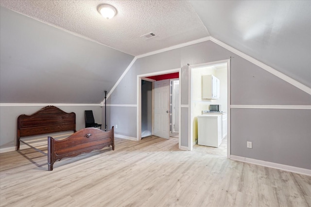 1505 Roane St, Covington, TN 38019 - additional living space featuring lofted ceiling, light wood finished floors, washer / clothes dryer, baseboards, and a textured ceiling