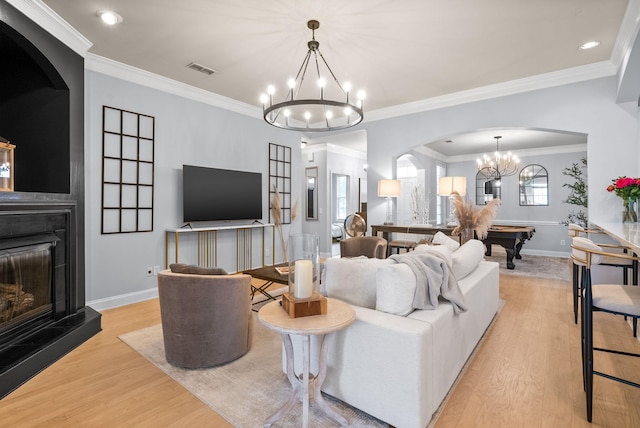 1113 Chickadee Cir, Hermitage, TN 37076 - living room featuring a chandelier, wood finished floors, a fireplace with raised hearth, arched walkways, and baseboards