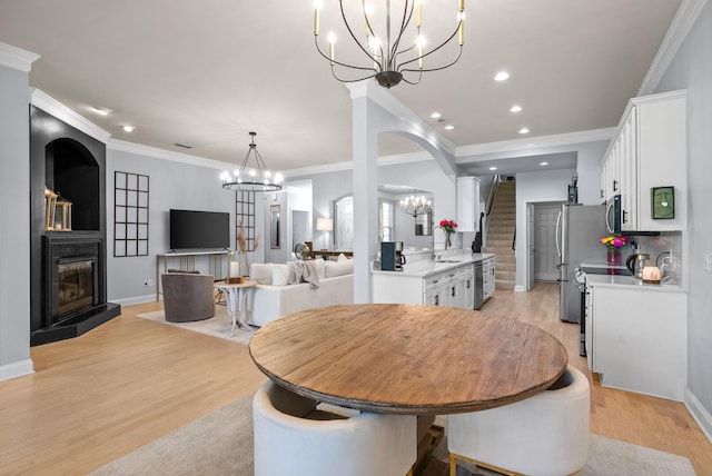 1113 Chickadee Cir, Hermitage, TN 37076 - dining room with a chandelier, light wood-type flooring, stairs, a fireplace with raised hearth, and recessed lighting