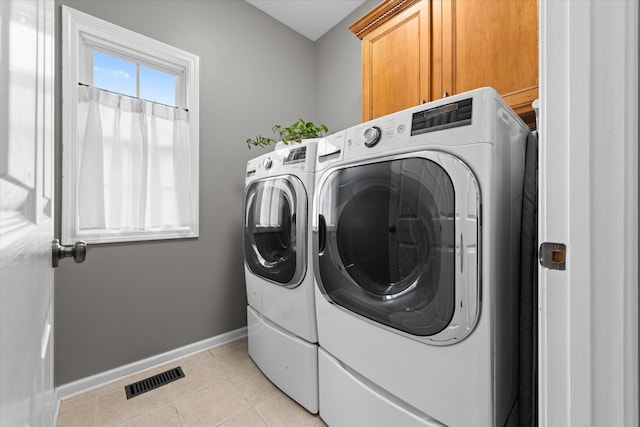 laundry area featuring cabinet space, baseboards, washing machine and dryer, and light tile patterned flooring