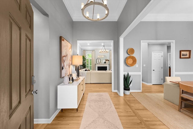 foyer featuring a chandelier, ornamental molding, light wood-type flooring, and a fireplace