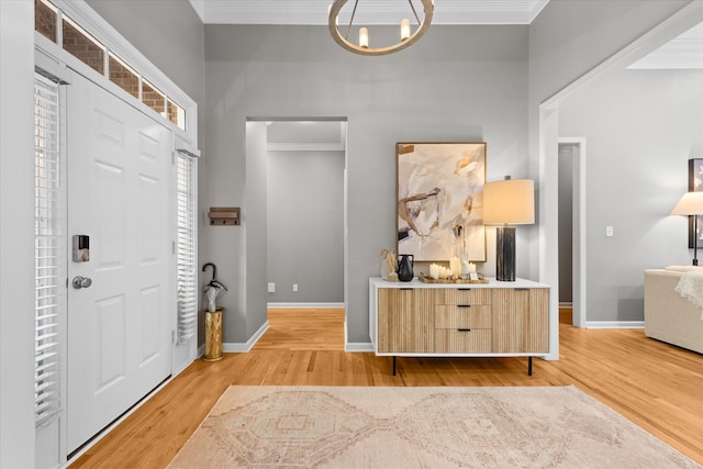 entrance foyer featuring a chandelier, light wood-type flooring, ornamental molding, and baseboards