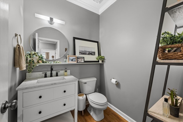 bathroom with crown molding, wood finished floors, toilet, vanity, and baseboards
