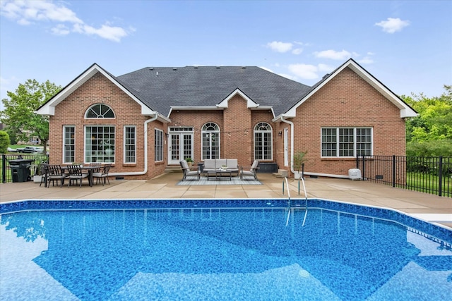 rear view of house with an outdoor hangout area, a patio area, brick siding, roof with shingles, and fence