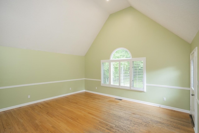 spare room with vaulted ceiling, light wood-style flooring, and baseboards