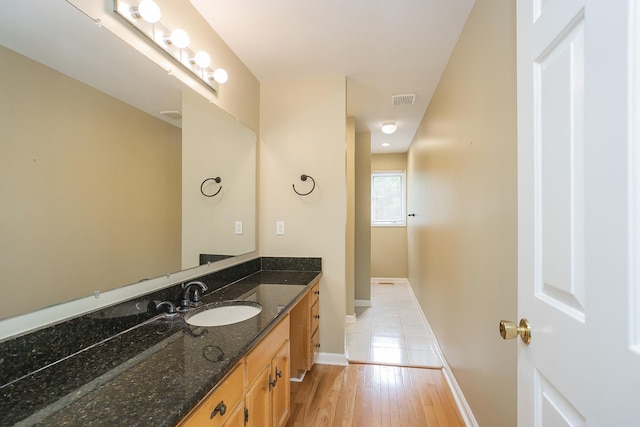 bathroom with baseboards, vanity, and wood finished floors