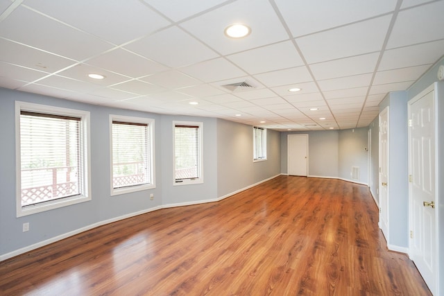 below grade area with wood finished floors, baseboards, recessed lighting, and a drop ceiling