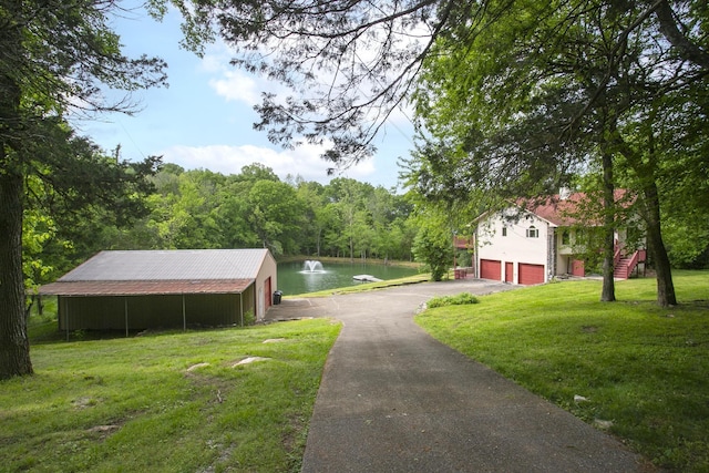 view of asphalt driveway featuring a water view and a wooded view