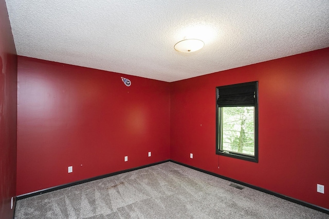 unfurnished room with a textured ceiling, carpet, and baseboards