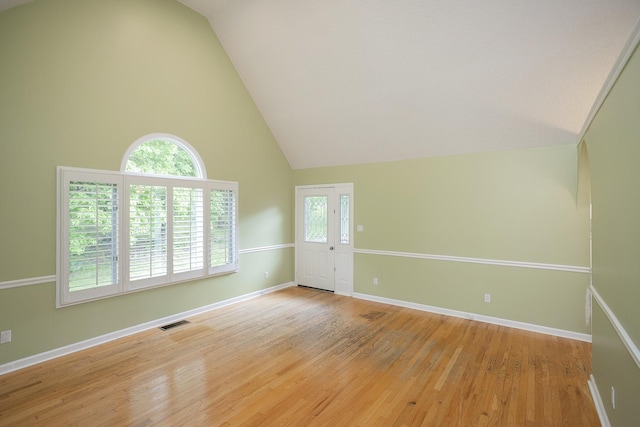 unfurnished room with light wood-style flooring, high vaulted ceiling, and baseboards