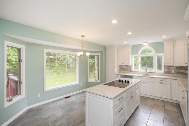 kitchen with a sink, black electric stovetop, backsplash, a chandelier, and recessed lighting