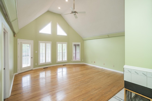 unfurnished living room with ceiling fan, light wood-style floors, high vaulted ceiling, and baseboards