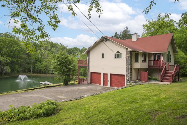 view of home's exterior with stucco siding, a water view, concrete driveway, an attached garage, and a lawn