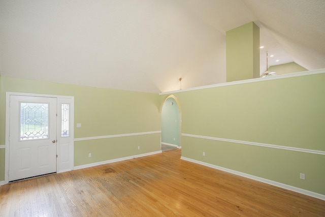 entryway featuring lofted ceiling, light wood finished floors, baseboards, and arched walkways