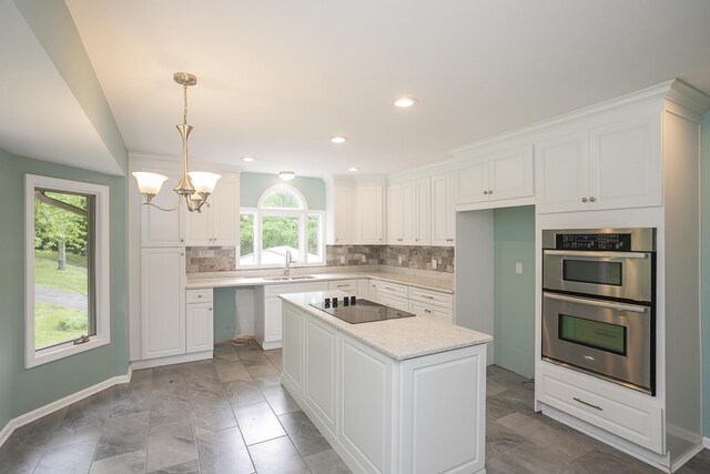 kitchen with black electric stovetop, a sink, stainless steel double oven, decorative backsplash, and white cabinets