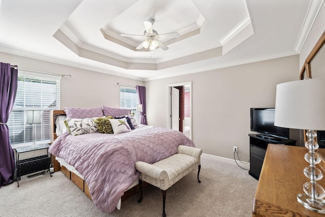 bedroom featuring crown molding, multiple windows, a tray ceiling, light colored carpet, and a ceiling fan