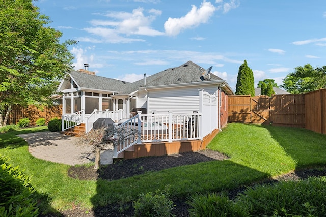 rear view of house featuring a sunroom, a wooden deck, a gate, roof with shingles, and a chimney