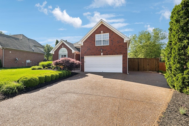 traditional-style house with a garage, brick siding, concrete driveway, and fence