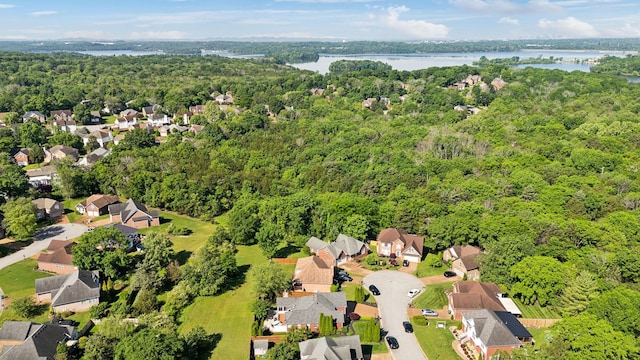 aerial perspective of suburban area featuring a forest and a large body of water