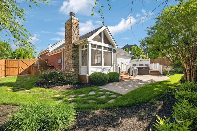 rear view of house with a gate, a sunroom, a chimney, and a patio area