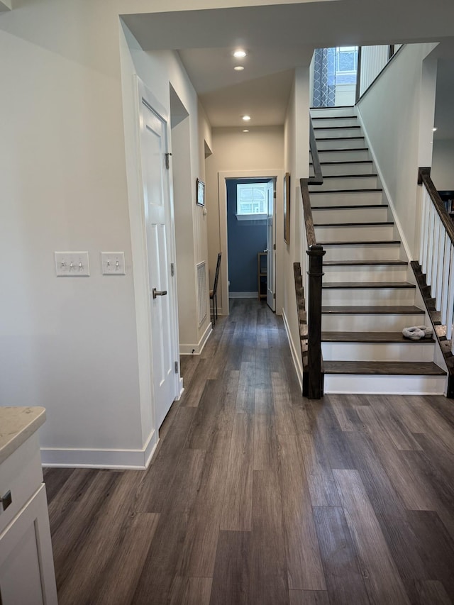 corridor featuring dark wood-style flooring, stairs, baseboards, and recessed lighting