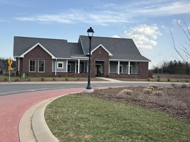 view of front of property with brick siding, a front lawn, and a porch