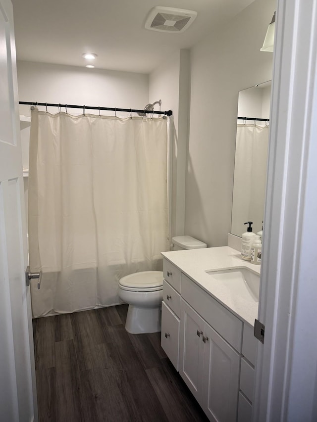 full bath with toilet, wood finished floors, vanity, shower / bath combo, and recessed lighting