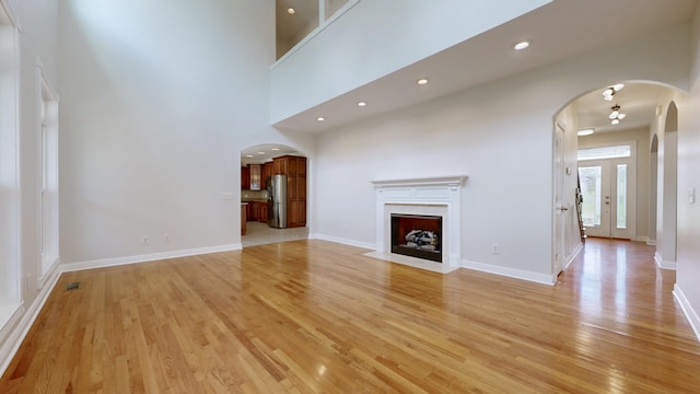 4050 Oak Pointe Dr, Pleasant View, TN 37146 - unfurnished living room featuring arched walkways, light wood-style floors, baseboards, a premium fireplace, and recessed lighting