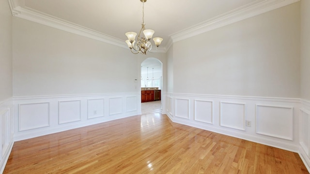 4050 Oak Pointe Dr, Pleasant View, TN 37146 - empty room with arched walkways, a chandelier, ornamental molding, a wainscoted wall, and light wood-style floors