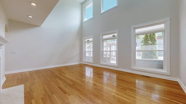 4050 Oak Pointe Dr, Pleasant View, TN 37146 - unfurnished living room featuring healthy amount of natural light, light wood-style flooring, baseboards, a towering ceiling, and a fireplace with flush hearth