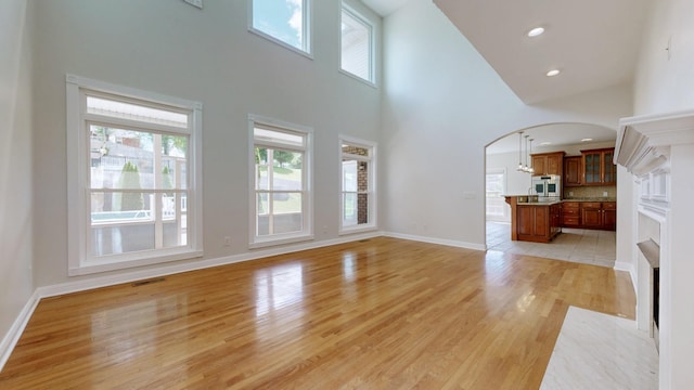 4050 Oak Pointe Dr, Pleasant View, TN 37146 - unfurnished living room with a high ceiling, healthy amount of natural light, arched walkways, light wood-style floors, and baseboards