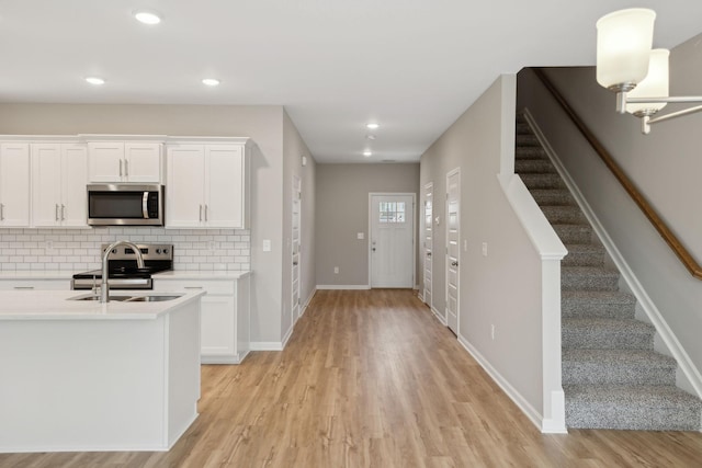 kitchen with appliances with stainless steel finishes, a sink, light wood-style flooring, light countertops, and recessed lighting