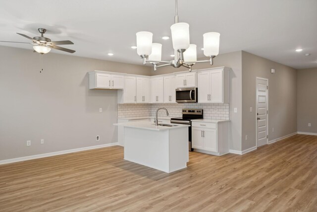 kitchen with stainless steel appliances, a sink, backsplash, recessed lighting, and white cabinets