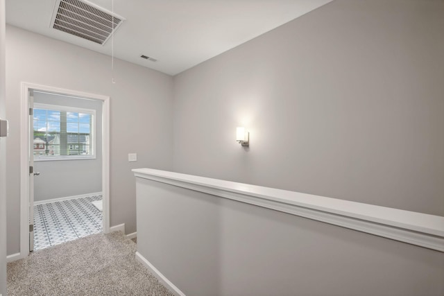 hall featuring attic access, carpet floors, baseboards, and an upstairs landing