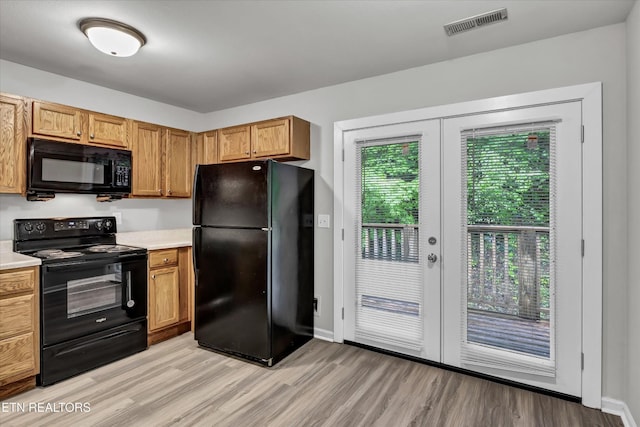 kitchen featuring black appliances, light wood finished floors, light countertops, and french doors