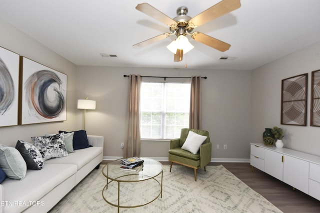 living room with a ceiling fan, baseboards, and dark wood-style floors