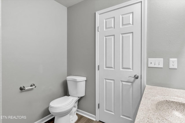 bathroom featuring toilet, wood finished floors, and baseboards