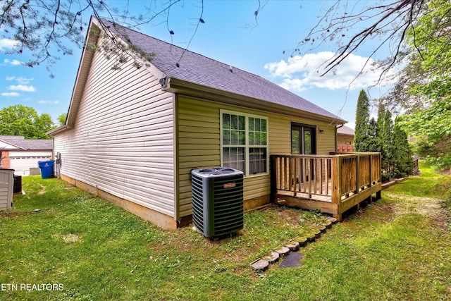 back of house with central air condition unit, a deck, a yard, and a shingled roof