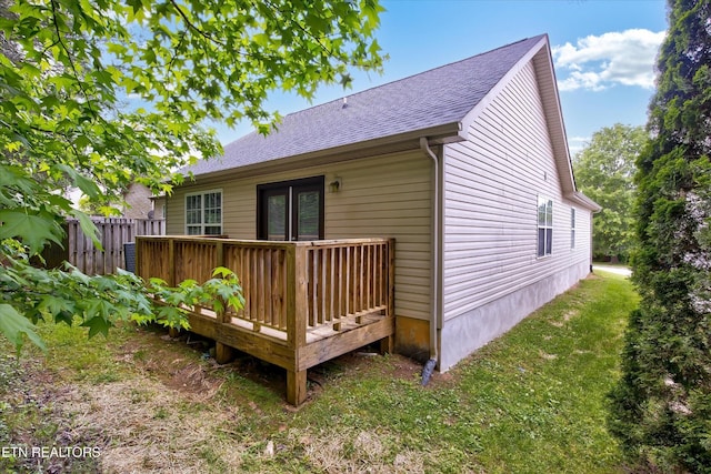 back of house with a deck, a shingled roof, and fence